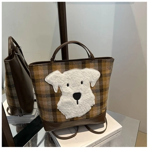 Detail of checkered tote bag with plush dog patch and premium leather trim finish
