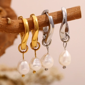 Detailed macro view of U-shaped gold and silver earrings with baroque pearl charms