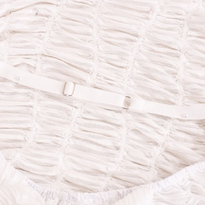Close-up of white ruched fabric texture with adjustable straps and pearl beads