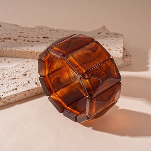 Detail of amber brown resin rectangular links on a textured light beige stone background