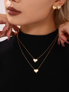 Detail of heart-shaped mother of pearl necklace and earrings set with gold beaded edges