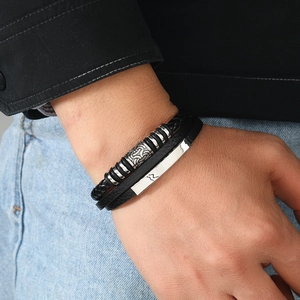 Close-up of men's black braided leather bracelets with silver metal accents on wrist