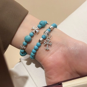Détail de bracelets en perles de turquoise avec un pendentif croix de style argent vintage