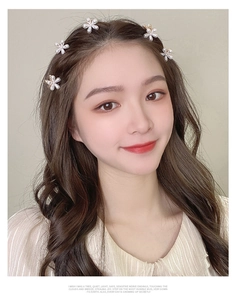 Close-up of five small pearl flower hair claws on dark wavy hair for styling