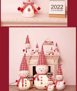 Close-up of glowing Christmas snowman dolls with plaid hats by a warm fireplace