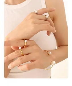 Detailed view of elegant gold open bangle and rings with white pearls on a knit texture