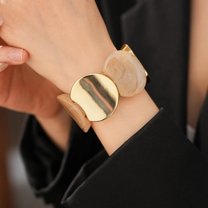 Detailed shot of golden metal and marble resin segments on a chunky elastic bracelet