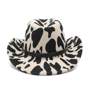 Detail of a wide-brimmed fedora hat featuring cow print pattern and leather buckle band