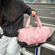 Pink travel fitness bag with black straps held by a model in an outdoor street setting