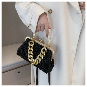 Detail of black pleated handbag with chunky gold chain strap and metallic handle