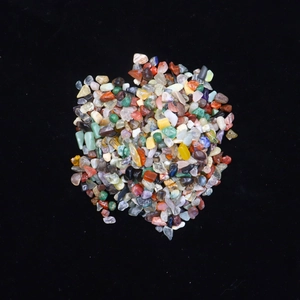 Macro view of polished natural crystal chips and mixed gemstones on black background
