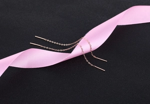 Detail of rose gold S925 silver threader earrings draped on soft pink silk fabric