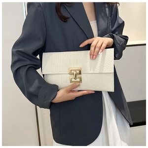 Detail of white crocodile pattern envelope clutch with golden metal turn-lock closure