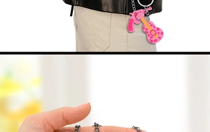 Detail view of pink guitar and pistol PVC keychains with silver metal rings on a waist