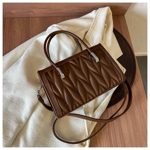 Detailed macro view of brown quilted tote bag with silver hardware and dual handles