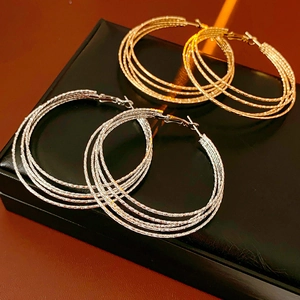 Detail view of multi-layer circular hoop earrings in gold and silver textured metal finish