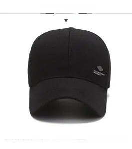 Detail of a black baseball cap featuring a twill fabric texture and metal shield badge