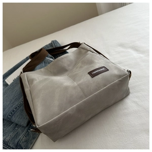 Detail of grey crossbody bag with brown strap and Fashion & Bags leather label