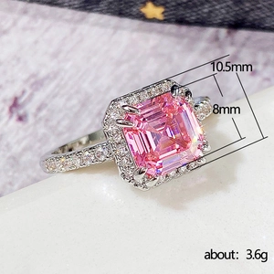 Elegant princess cut pink gemstone ring with halo diamonds on a white marble surface