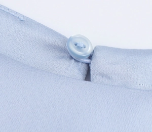 Detailed macro view of light blue satin fabric with a matching resin button and fine stitching