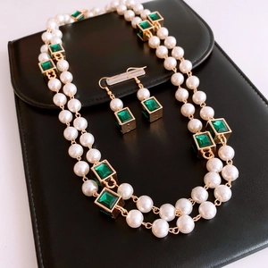 Detail of vintage gold necklace and earring set with pearls and green square pendants