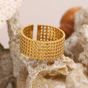 Detailed view of 18K gold mesh texture ring on natural stone background in warm light
