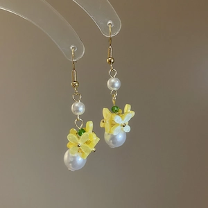 Detail of yellow flower earrings with white pearls and gold hooks for spring