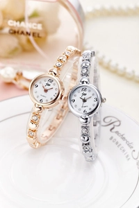 Detailed view of silver and gold quartz watches with heart shaped rhinestones on a white plate