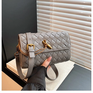 Detail of woven gray leather crossbody bag with a distinctive gold knot metal clasp