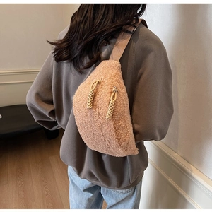 Detail of beige lamb wool crossbody chest bag with woven zipper pull on grey sweatshirt