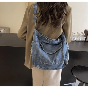 Détail du sac fourre-tout en denim bleu avec bords effilochés vintage et large bandoulière