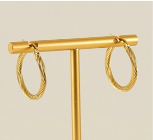 Detailed view of golden twisted rope hoop earrings displayed on a professional jewelry stand