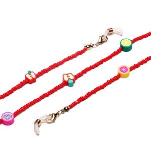 Detail of red beaded eyeglass chain with handmade clay fruit charms and golden clasps