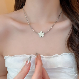 Detail of flower pendant necklace with white enamel petals and small diamond on neck