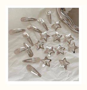 Close-up of 18 silver star and teardrop metal hair clips on a textured background