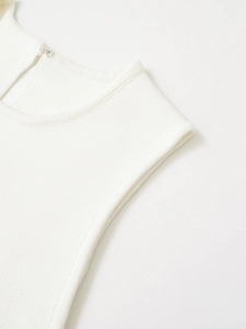 Gros plan d'un haut en maille blanche montrant les coutures et l'agrafe en métal au col