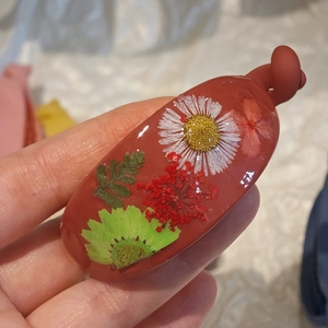 Close-up of resin banana clip with real dried flowers and leaves inside the red frame