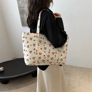 Minimalist cream canvas tote bag with red cherry print worn by a model in a modern interior