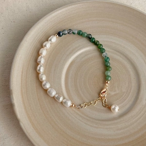 Detail view of Baroque pearl and green agate bead bracelet on a ceramic plate