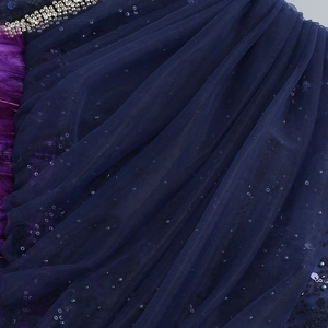 Détail de paillettes sur tulle avec plumes violettes et broderies de perles argentées