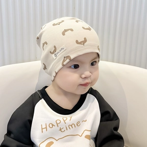 Detail of beige cotton knit baby hat with cartoon dog print worn by an infant