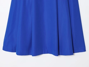Détail d'une jupe midi plissée bleu roi montrant la texture sergé et l'ourlet précis