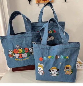 Detail of embroidered cartoon characters on washed denim tote bags with quality stitching