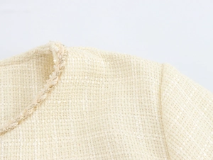 Détail de la texture en tweed avec franges sur l'épaule et l'encolure du vêtement