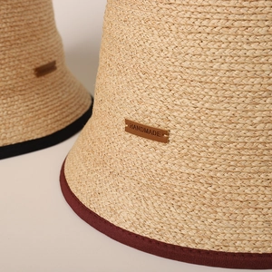 Cappello a secchiello in rafia fatto a mano con bordo a contrasto e etichetta in cuoio
