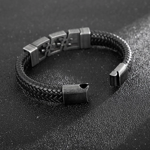 Detail of black braided leather men's bracelet with dark metal clasp and punk style texture