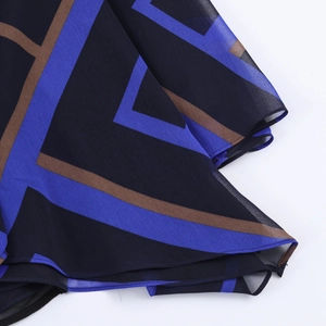 Detailopname van bedrukte chiffonstof met blauwe en bruine geometrische vormen