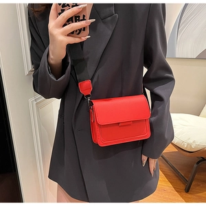 Chic red square leather crossbody bag with adjustable wide black strap on female model