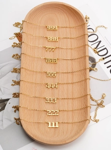 Detailed display of nine gold stainless steel angel number necklaces on a wooden tray