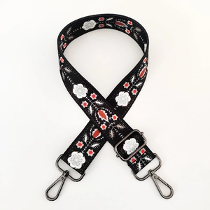Detail of floral embroidery on woven bag strap with gunmetal swivel snap hooks